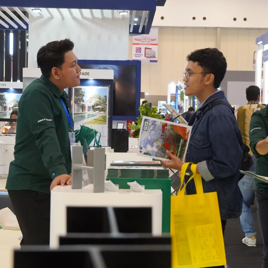 GYS representative discussing product features with a visitor at PT Garuda Yamato Steel booth during Konstruksi Indonesia 2024, showcasing innovative structural steel solutions.