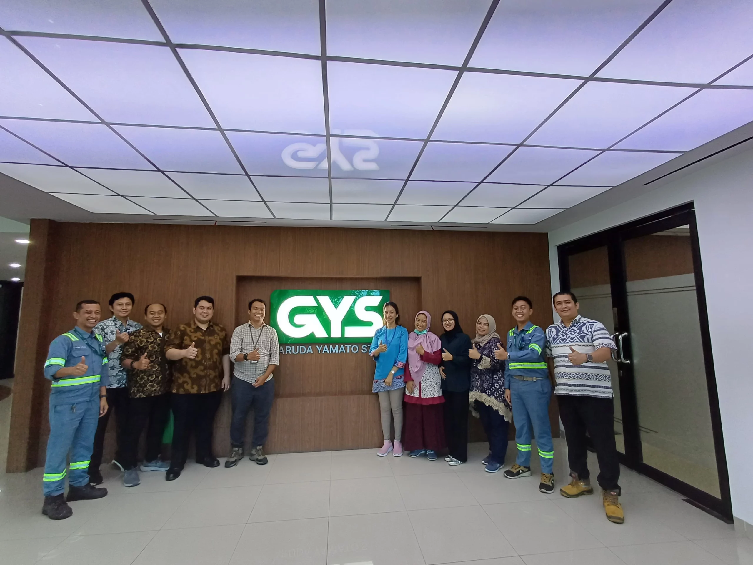 BSPJI and GYS Team Posing In Front Of GYS Logo at GYS Lobby HO